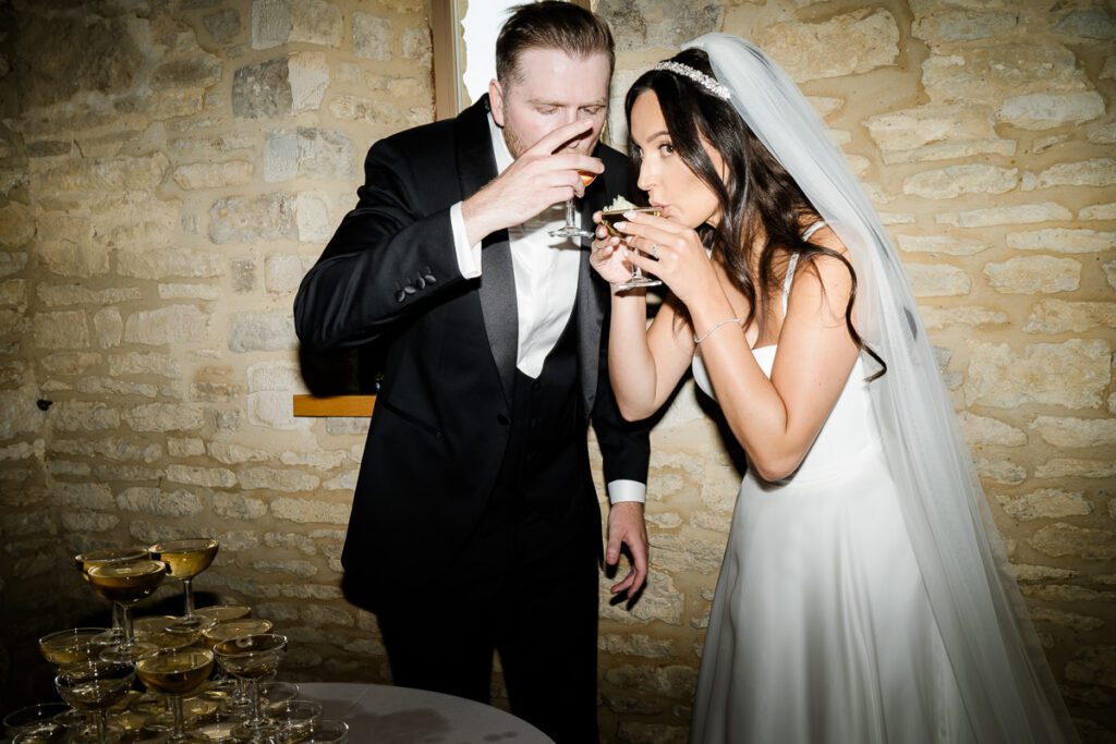 a bride and groom sip champagne after pouring a champagne tower at their wedding at Caswell House