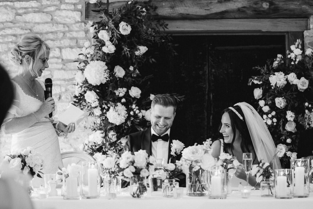 the bride and groom share a laugh as the mother of the bride delivers a speech at Caswell House
