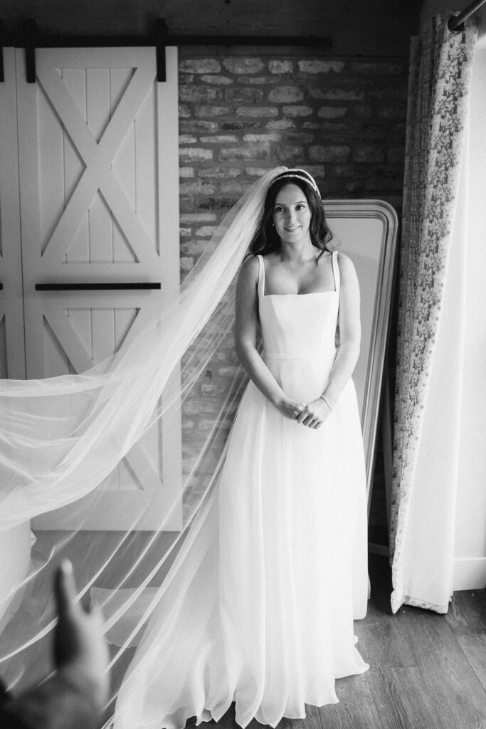 a bride stands in the honeymoon suite at Caswell House, her veil is stretched out from her to the front of the photo