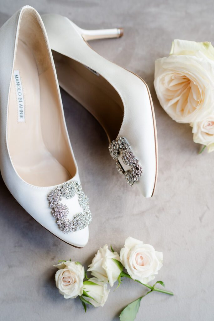 flat lay photograph of white Manolo Blahnik wedding shoes with white roses