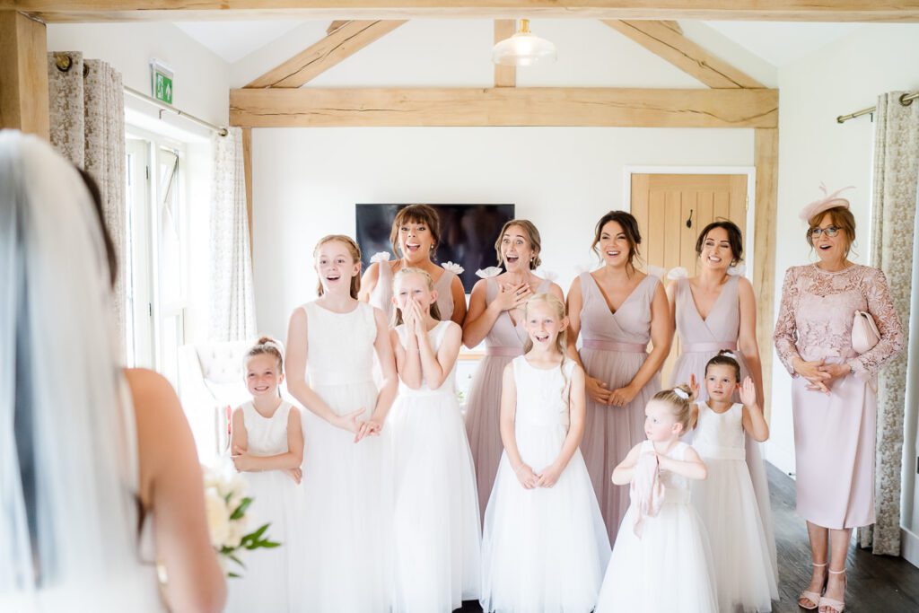 bridesmaids react to seeing their friend in her wedding dress for the first time. They're standing in the honeymoon suite at Caswell House