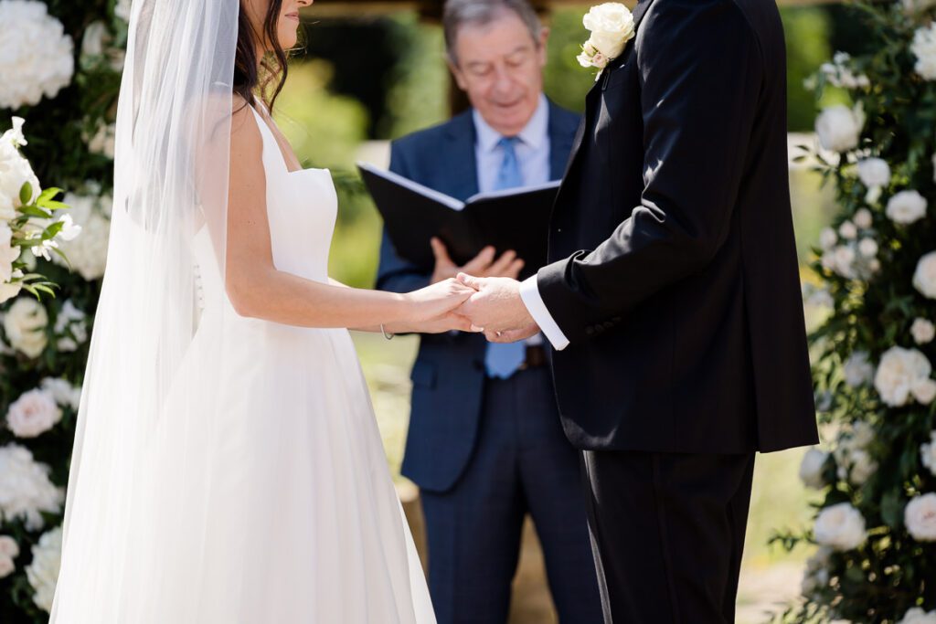 close up photograph of a bride and groom holding hands during their wedding ceremony at Caswell House