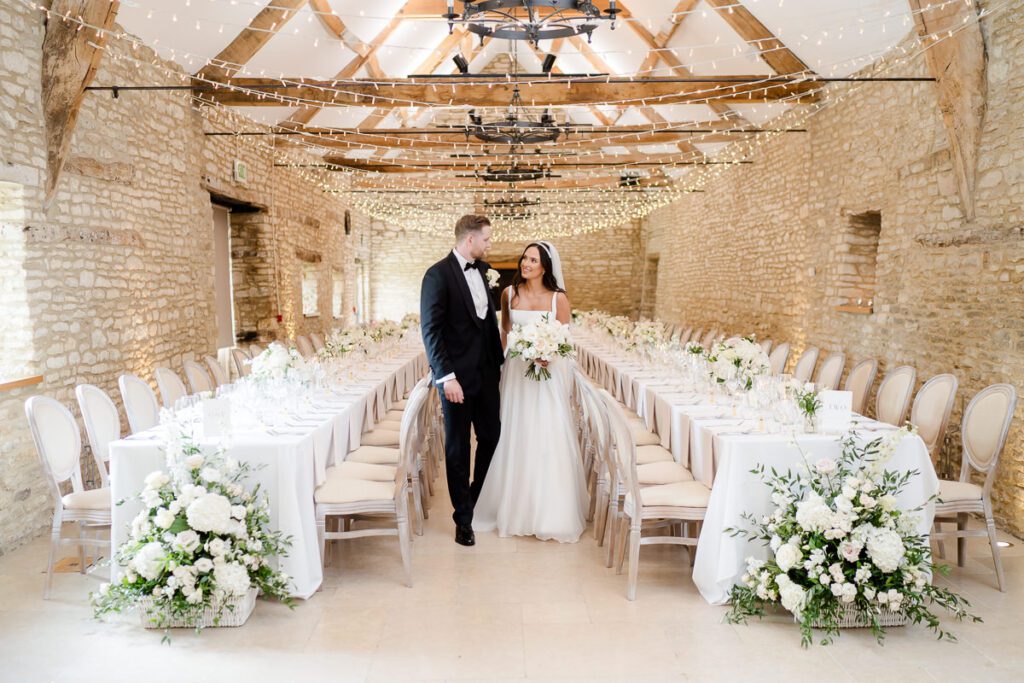 a bride and groom look around Caswell House dining room set for their wedding breakfast with long banqueting tables.