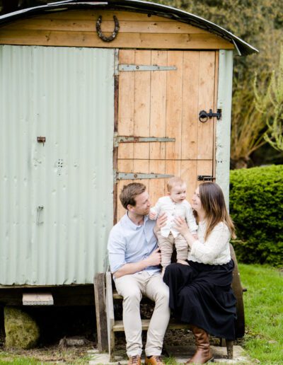 a couple sit on a step outside a sheperds hut during a family portrait shoot near Salisbury Wiltshire