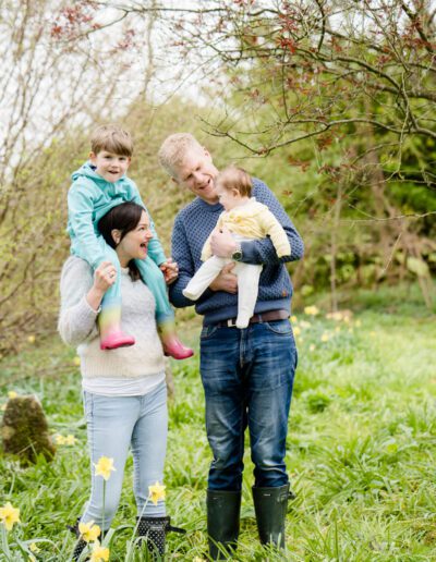 a family stand together among daffodils during a family photo shoot near Salisbury Wiltshire