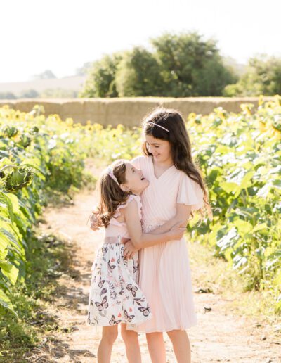 two sisters hug in a sunflower field in Salisbury Wiltshire