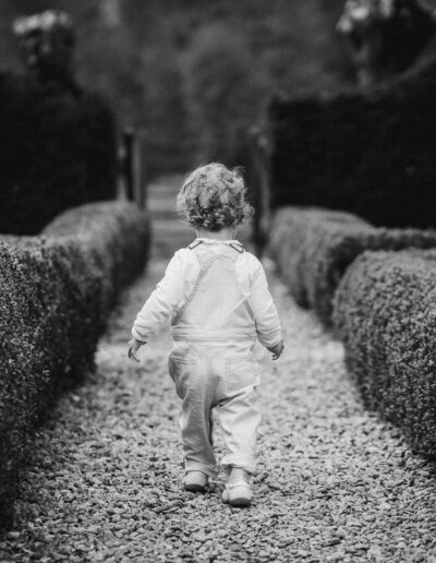 a black and white portrait of a toddler walking down a garden path in Wiltshire
