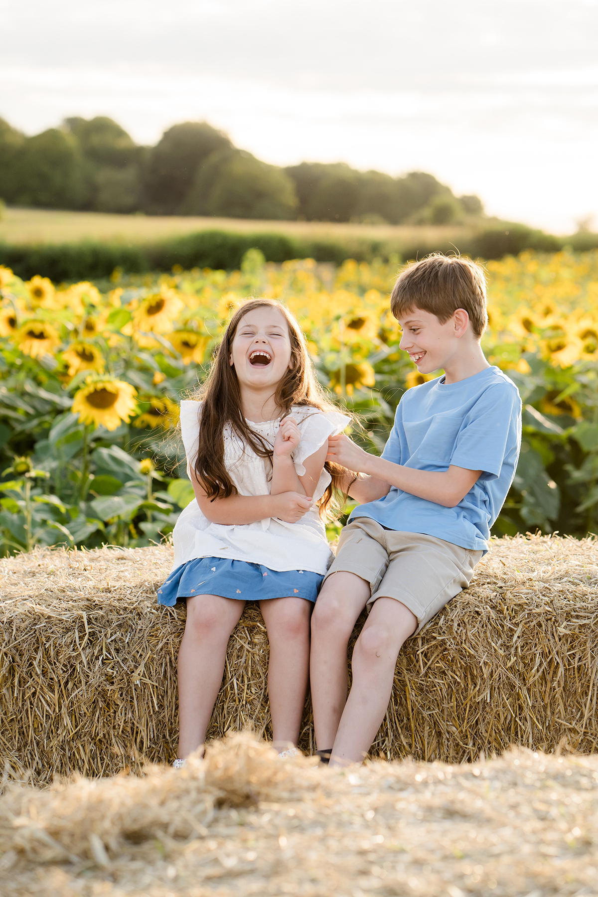 brother and sister laughing together at Salisbury Sunflower field during a family portrait shoot by Lydia Stamps Photography