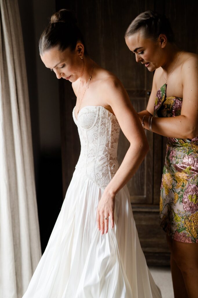 Bride getting dressed in a Sarah Seven wedding dress a bride and groom exchange vows during their wedding ceremony at Bowerchalke Barn Salisbury by Wiltshire wedding photographer Lydia Stamps Photography