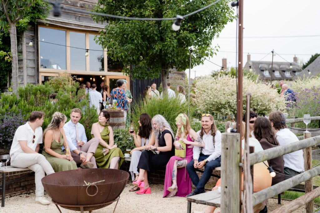 wedding guests seated around a fire pit at Bowerchalke Barn near Salisbury Wiltshire photo by Lydia Stamps Photography